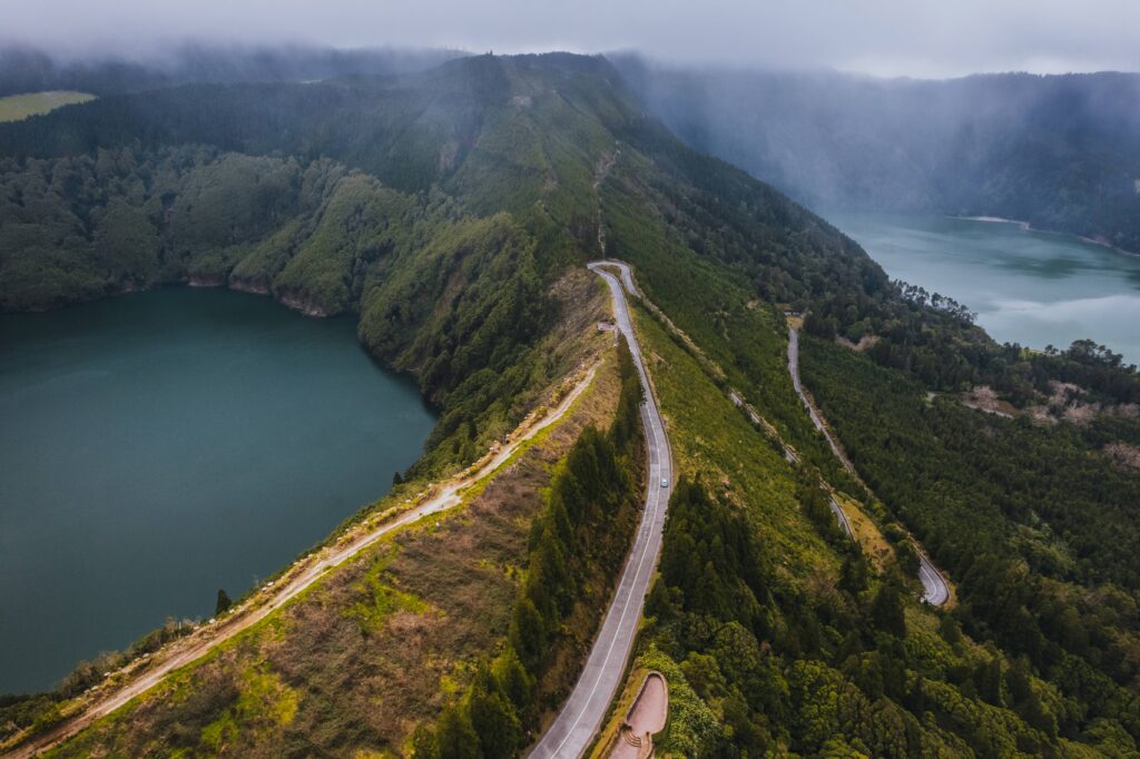 Automóvel numa estrada panorâmica junto à Lagoa do Fogo, rodeado pela paisagem vulcânica de São Miguel.