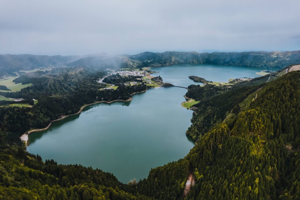 Aerial view of Sete Cidades Lake in São Miguel, with green vegetation and mist over the volcanic crater.