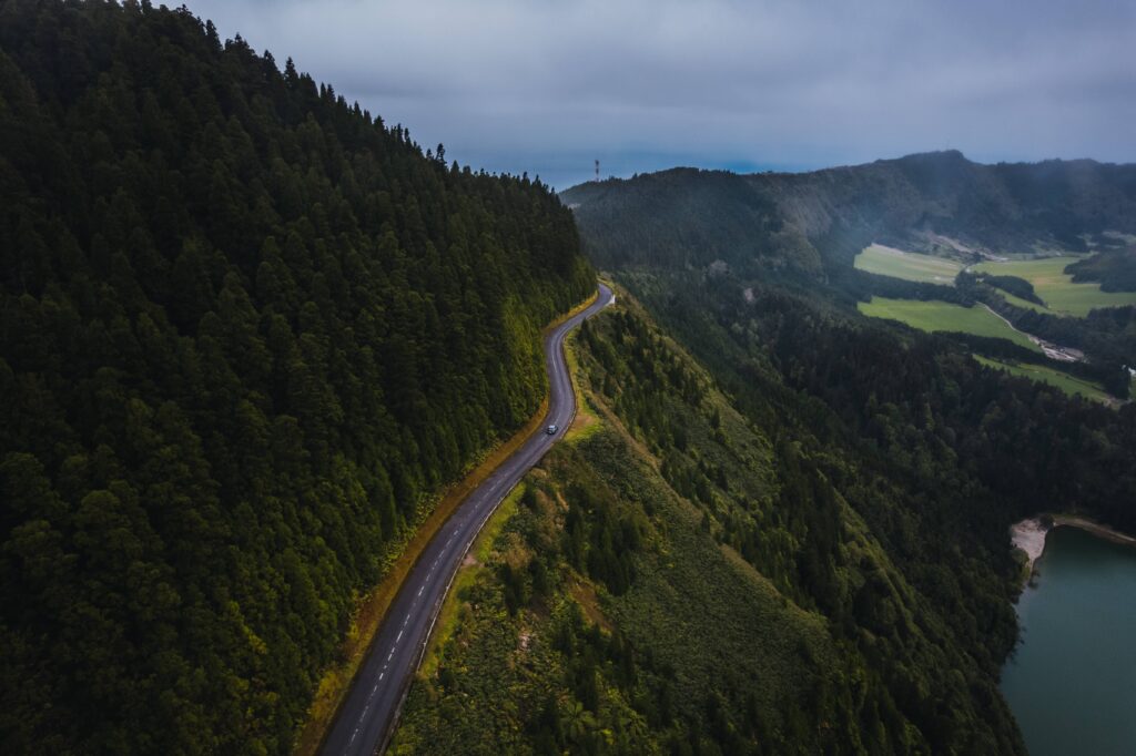 Scenic road in São Miguel surrounded by green vegetation and overlooking the Atlantic Ocean.