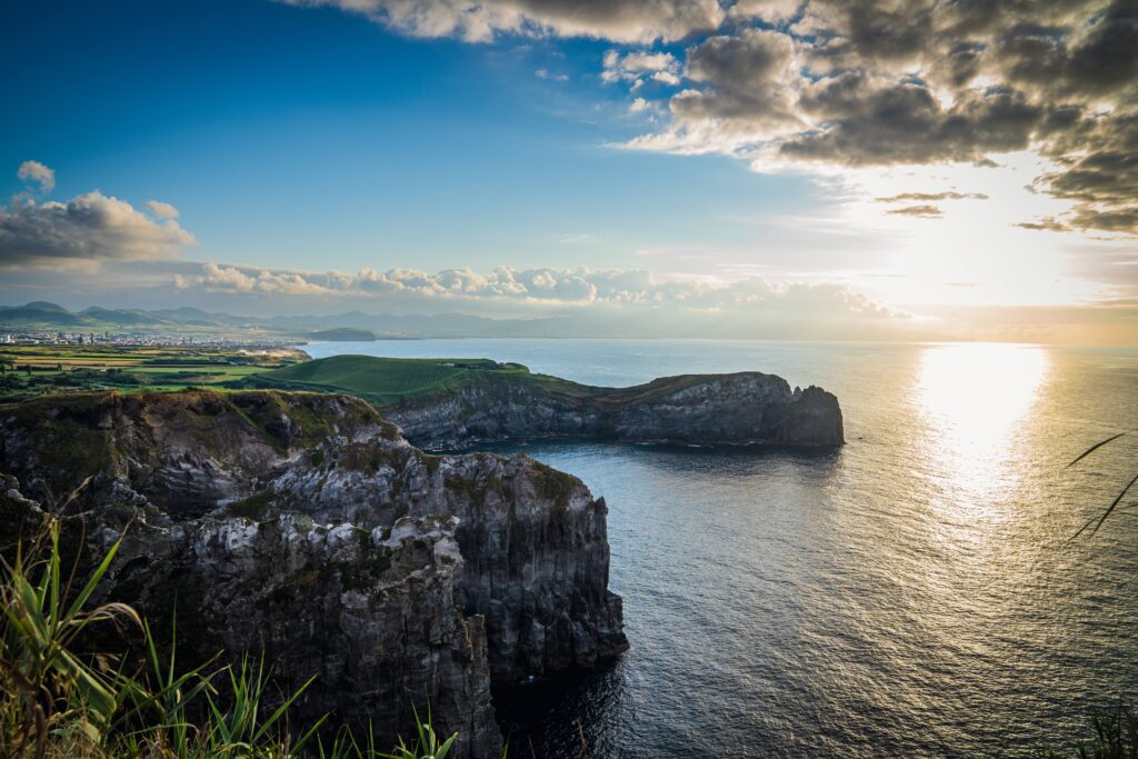 Coastal road in São Miguel surrounded by the island's green landscape and the Atlantic Ocean.