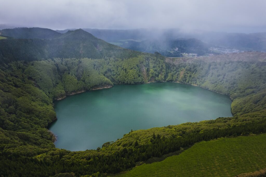 São Miguel landscape on a winter day, with green vegetation, a wet road and mist over the mountains.