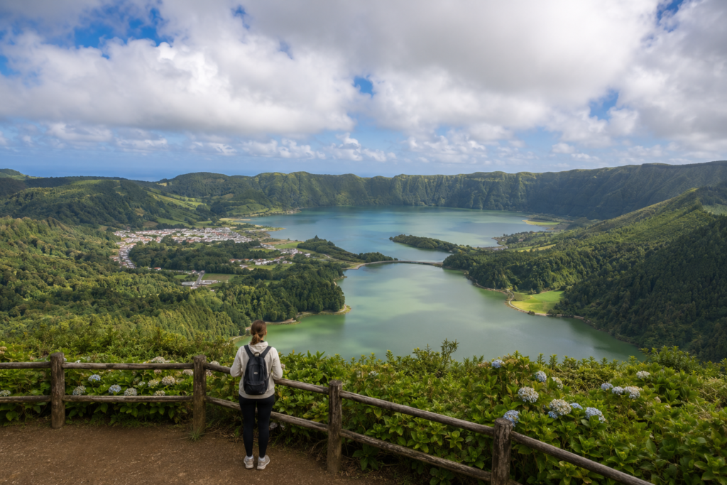 Visitante a contemplar a Lagoa das Sete Cidades e a paisagem vulcânica envolvente em São Miguel.