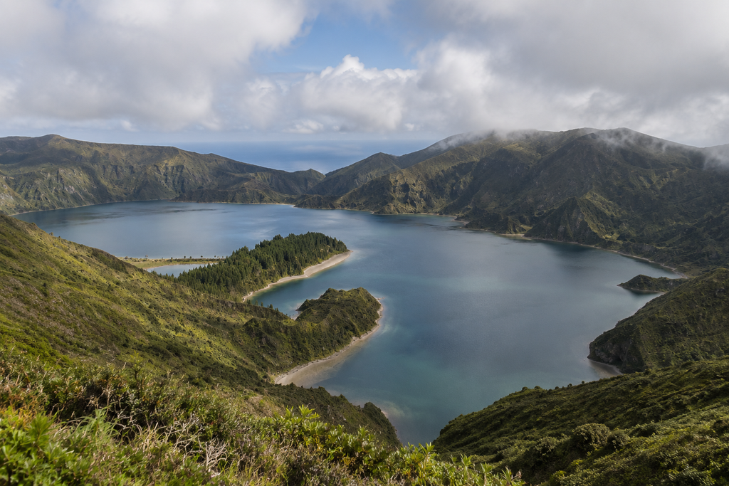 Vista panorâmica da Lagoa do Fogo rodeada pelas encostas verdes da caldeira vulcânica em São Miguel.